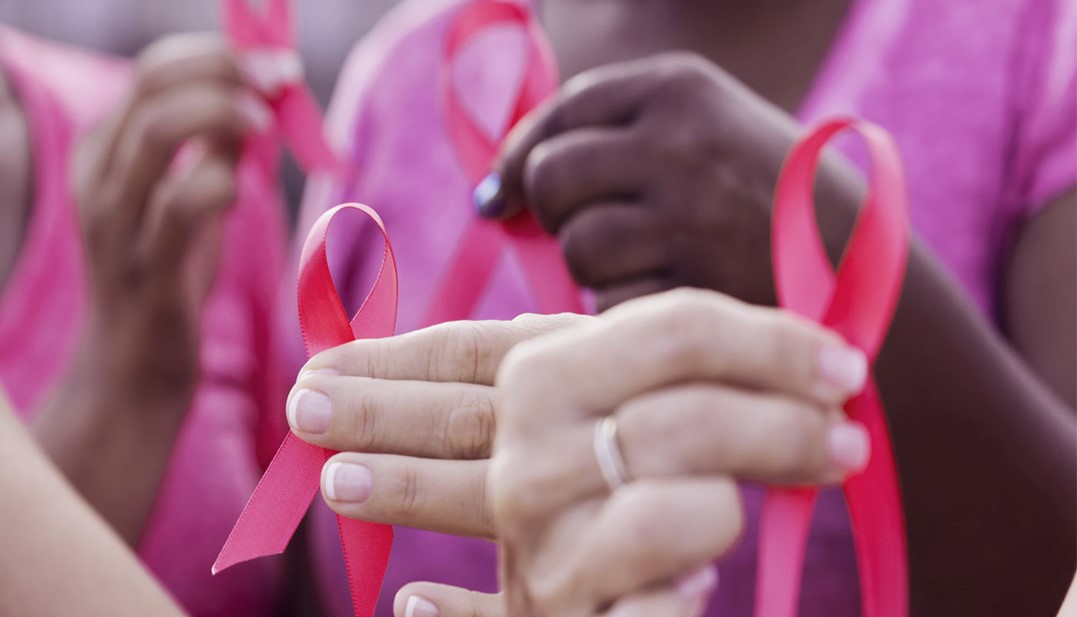 Mulheres brancas e negras vestidas de rosa e segudando o laço rosa que representam a ação do outrubro rosa